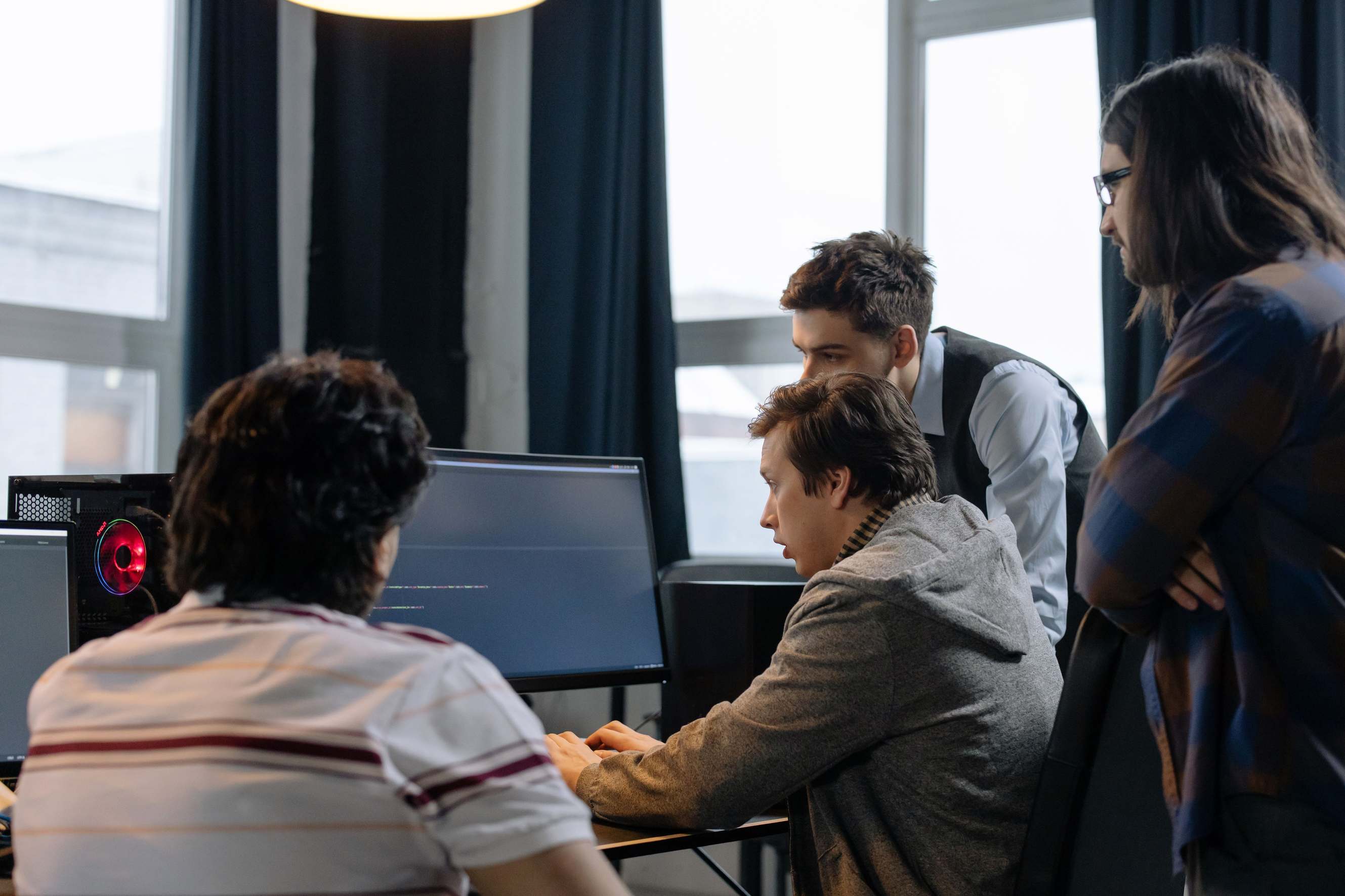 Developers reviewing a laptop screen together indoors — group of developers working together on a computer programming project indoors